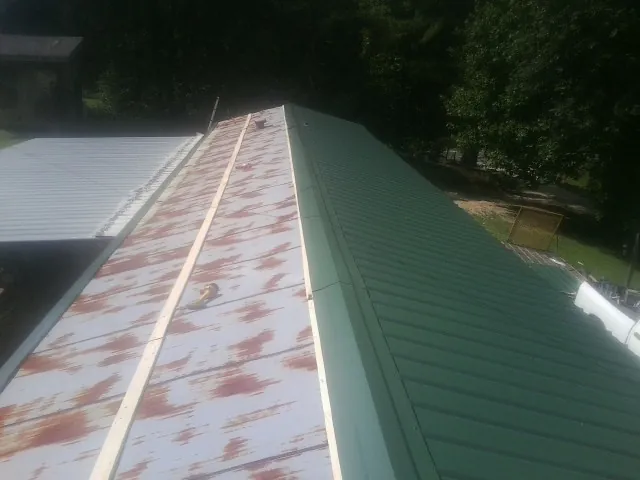 Old rusted panels beside newly installed green metal roofing — Wind Damage Roof Repair by Roofing Brothers in South Haven