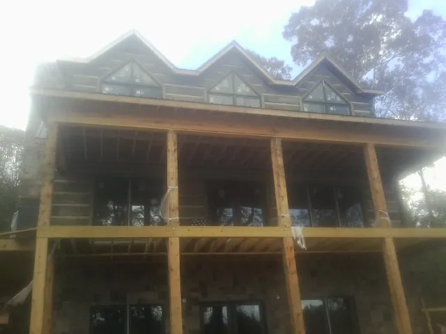Dormers and porch framing on a large log home under construction — Roof Coating work by our crew in South Haven