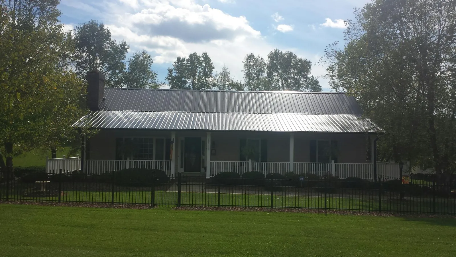 Gray metal roof on a brick ranch with a full width front porch — Gutter Guard Installation work by our crew in South Haven