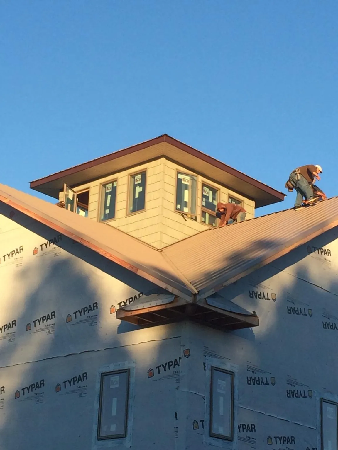 Roofers working around a rooftop cupola on a new metal roof at sunset — Roof Waterproofing in South Haven by Roofing Brothers